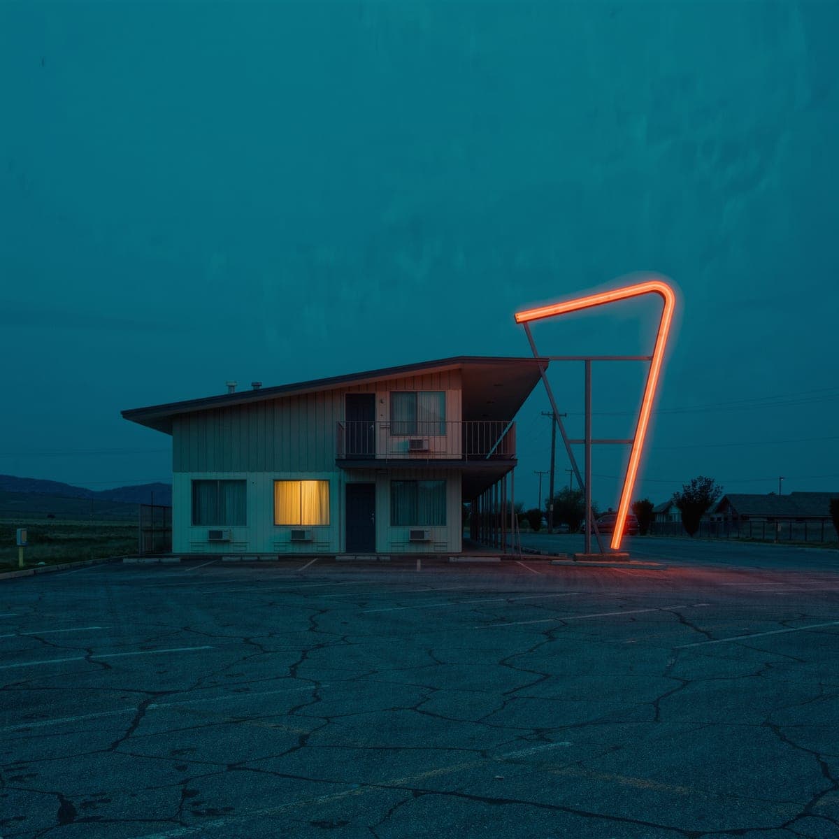 Album cover: a roadside motel at blue hour with one lit window and an empty lot.