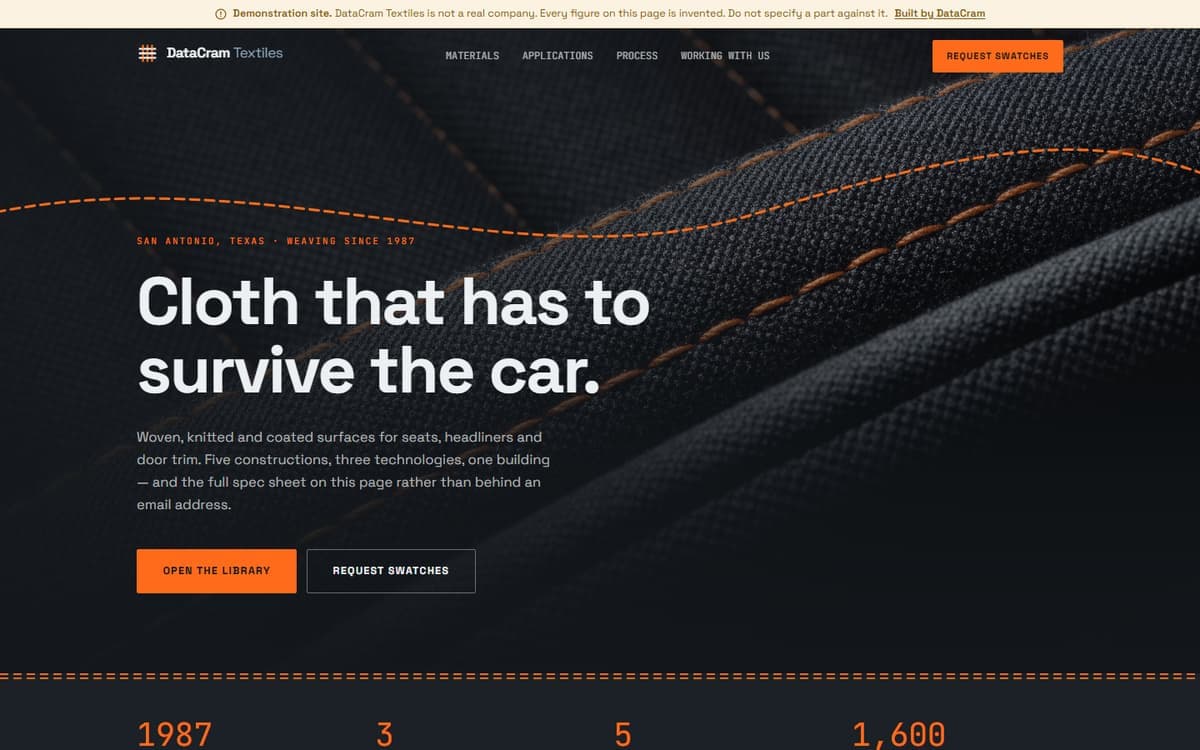 The DataCram Textiles demo site: a disclosure bar, a woven-glyph wordmark, and a headline reading 'Cloth that has to survive the car' over a macro photograph of charcoal seat fabric with orange contrast stitching.