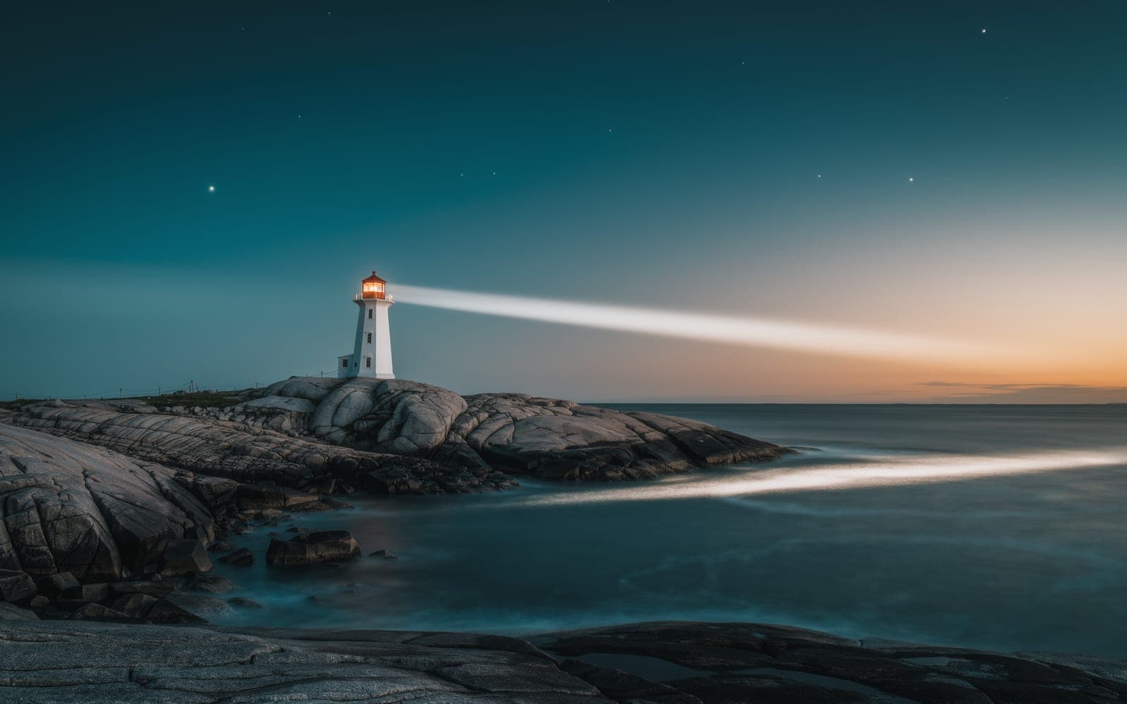 A white lighthouse on a rocky headland at dusk, its beam sweeping across a calm sea as the first stars appear
