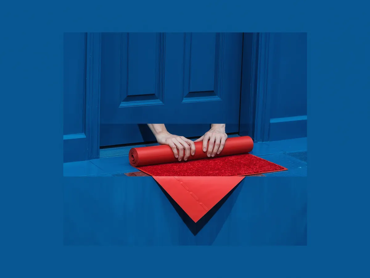 Hands rolling out a red doormat in front of a door.