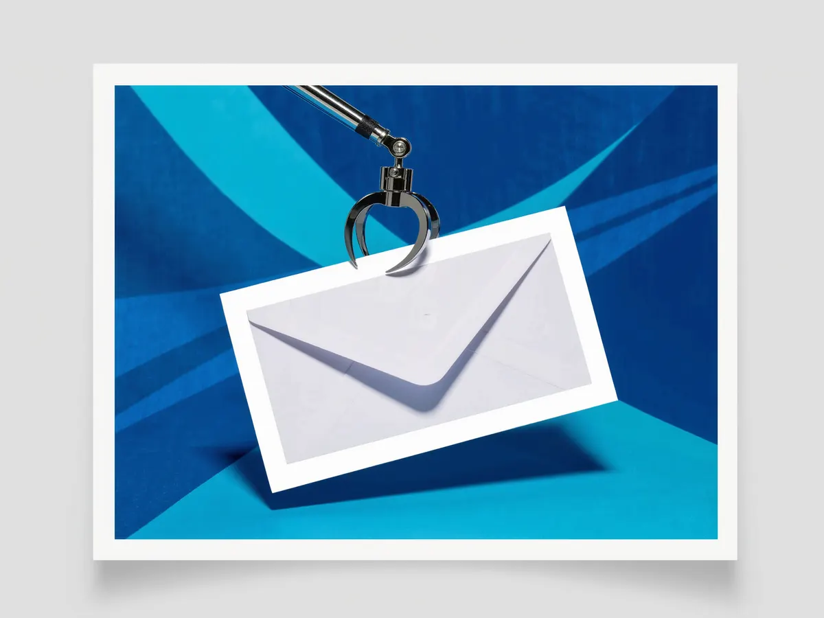 A small chrome mechanical claw lifting the flap of a plain white envelope.