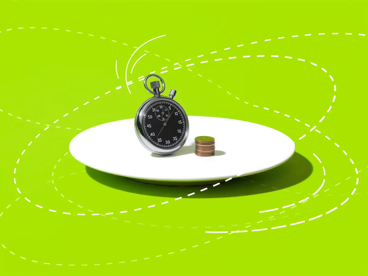 A stopwatch beside a short stack of coins against a bright green background.