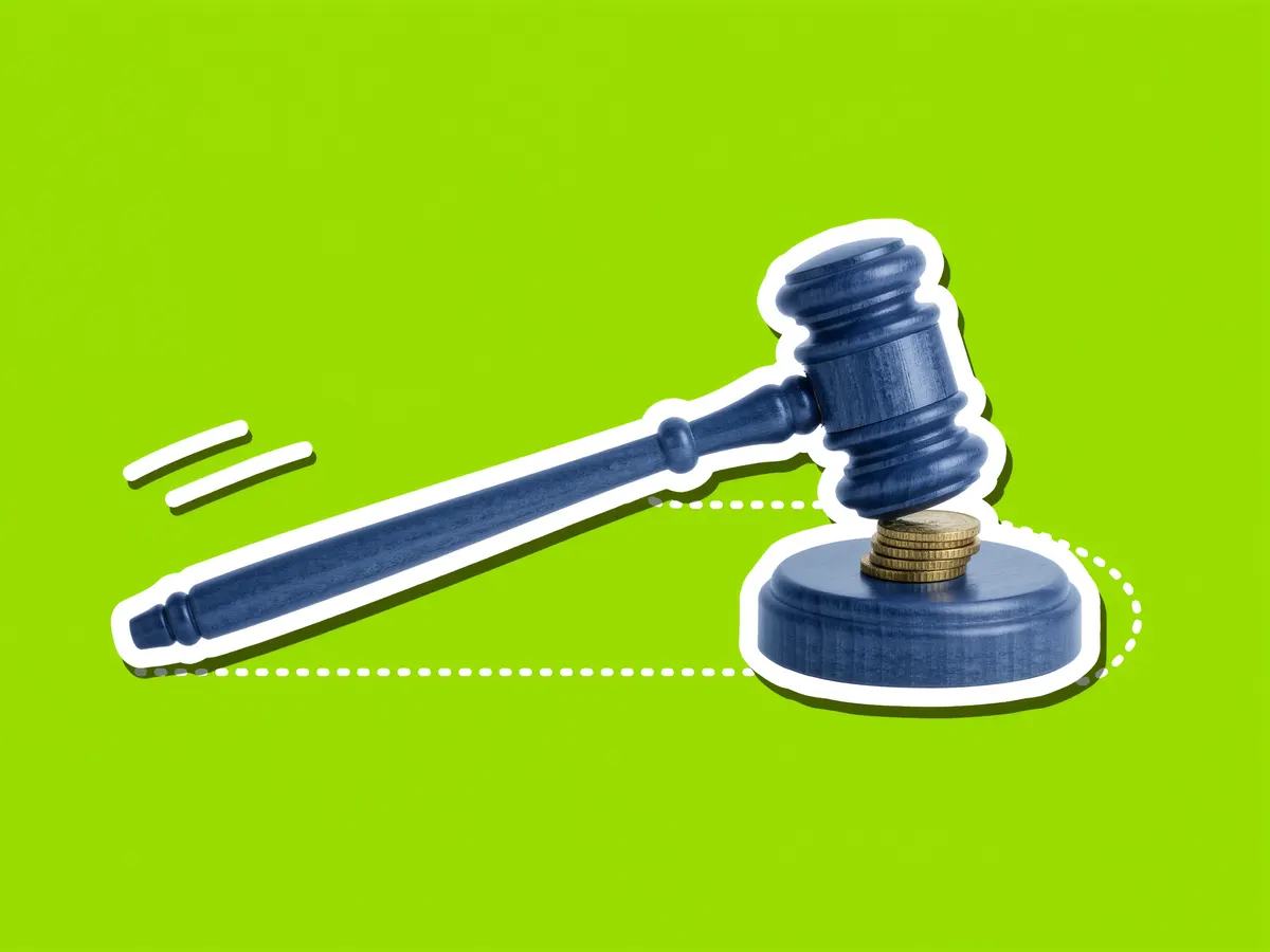 An auctioneer's gavel beside a short stack of gold coins on a bright green background.