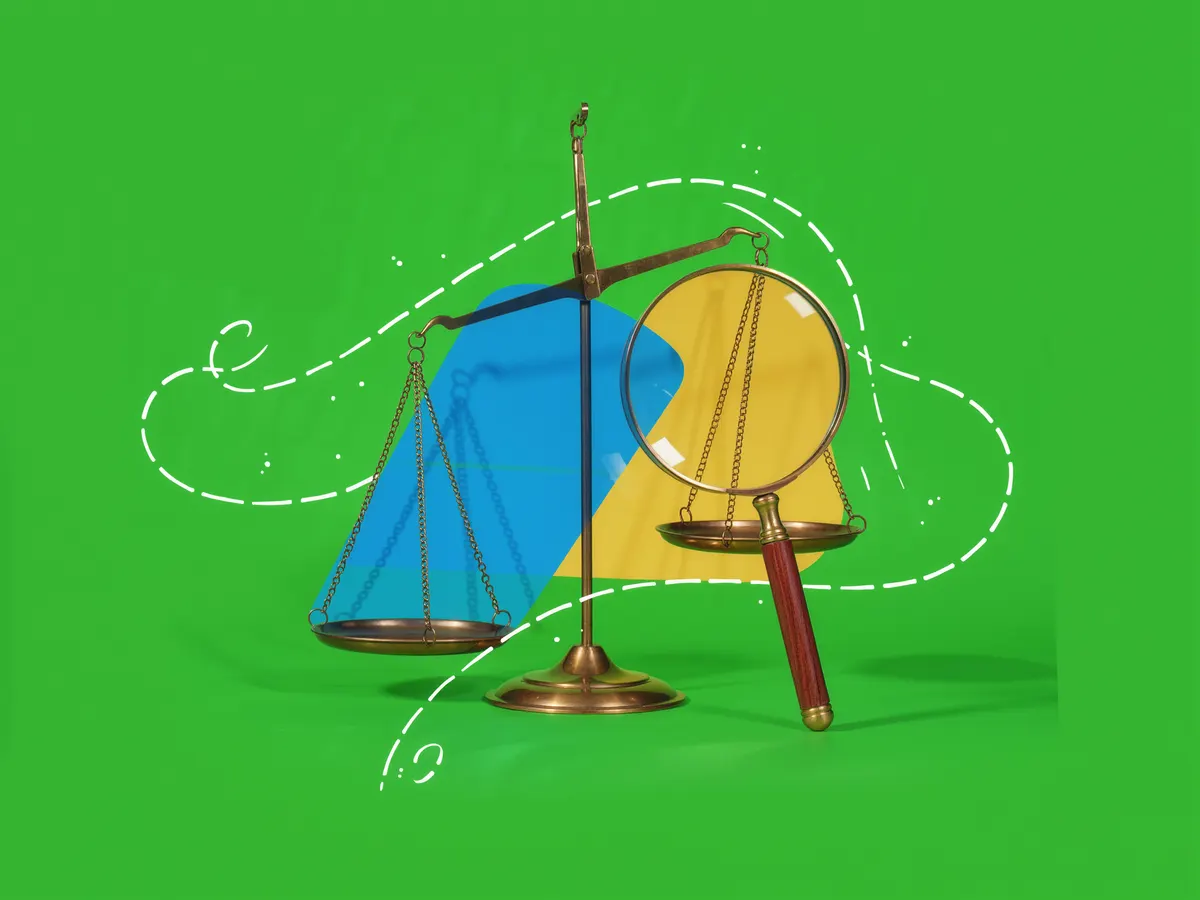 A brass balance scale beside a large magnifying glass on a green background.