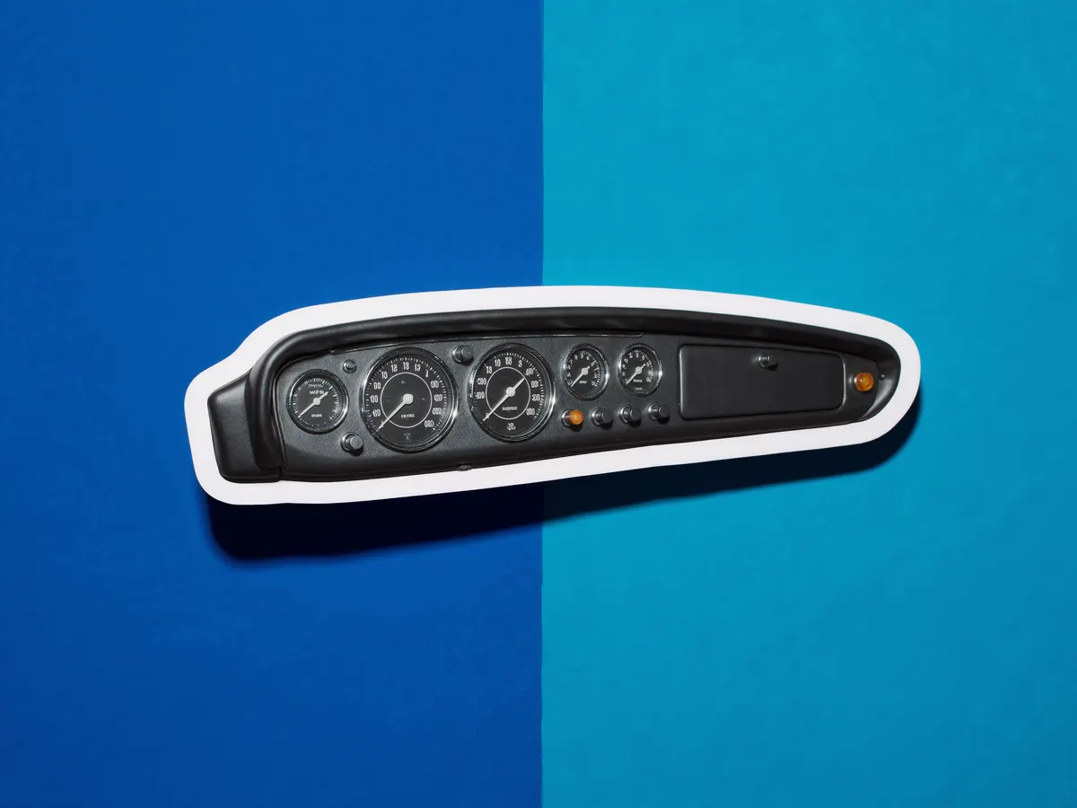 A vintage car dashboard with round gauges, cut out over a blue duotone photograph.