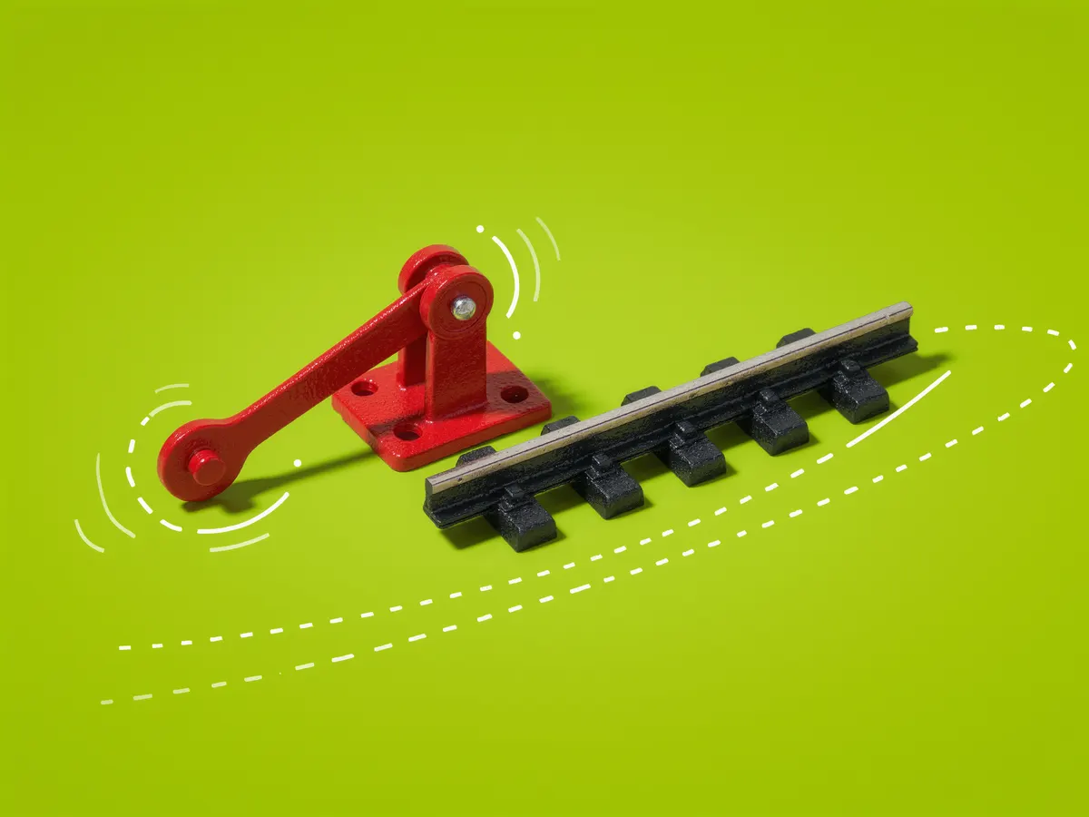 A red railroad switch stand beside a track that splits in two, on a lime green background.