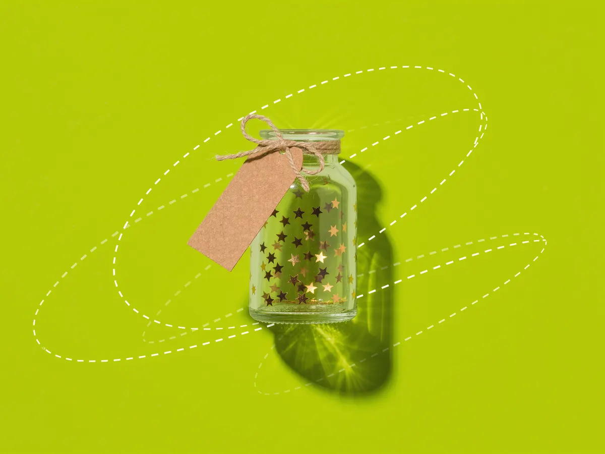A glass jar of gold star stickers with a blank paper tag on a lime green background.