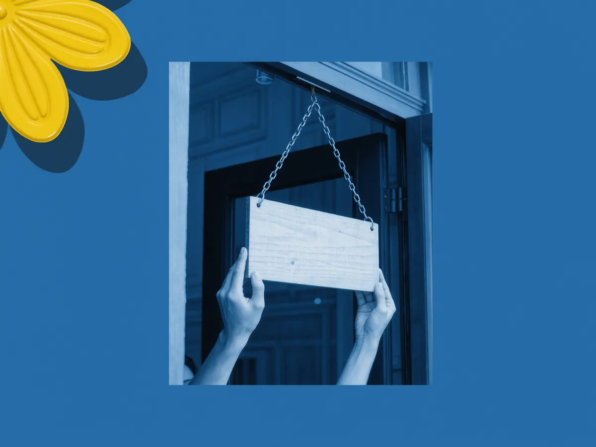 Hands hanging a blank wooden shop sign on chains above a doorway.